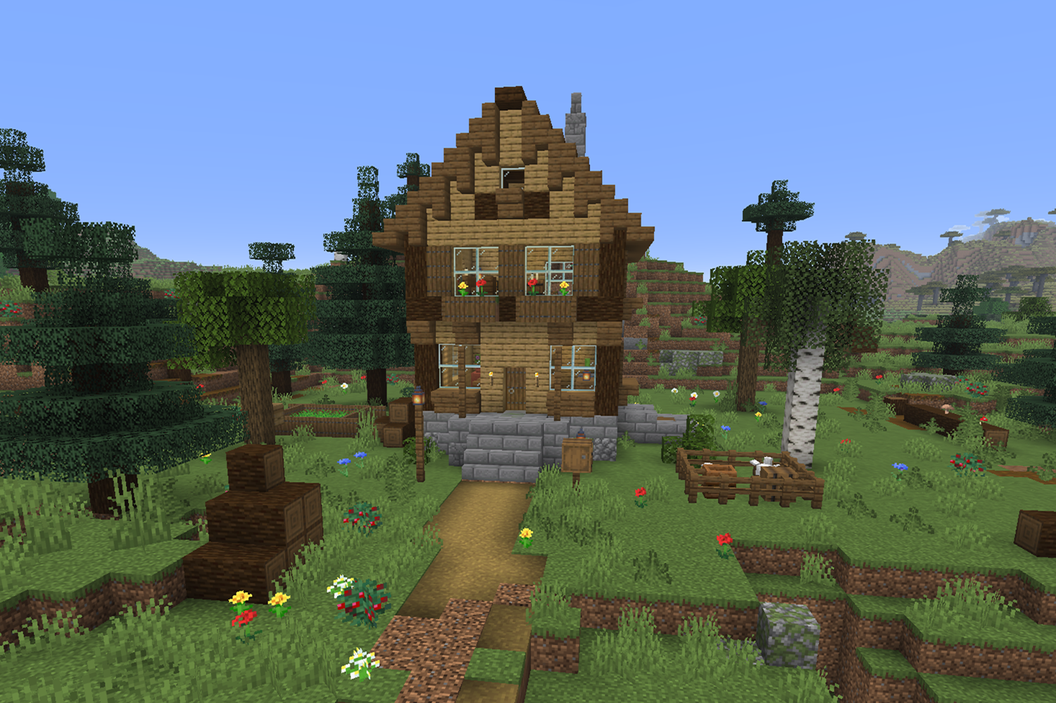Small multilevel wooden Minecraft house with a stone basement, second floor with flower boxes, steep roof, outside cellar door, and chicken pen in the yard