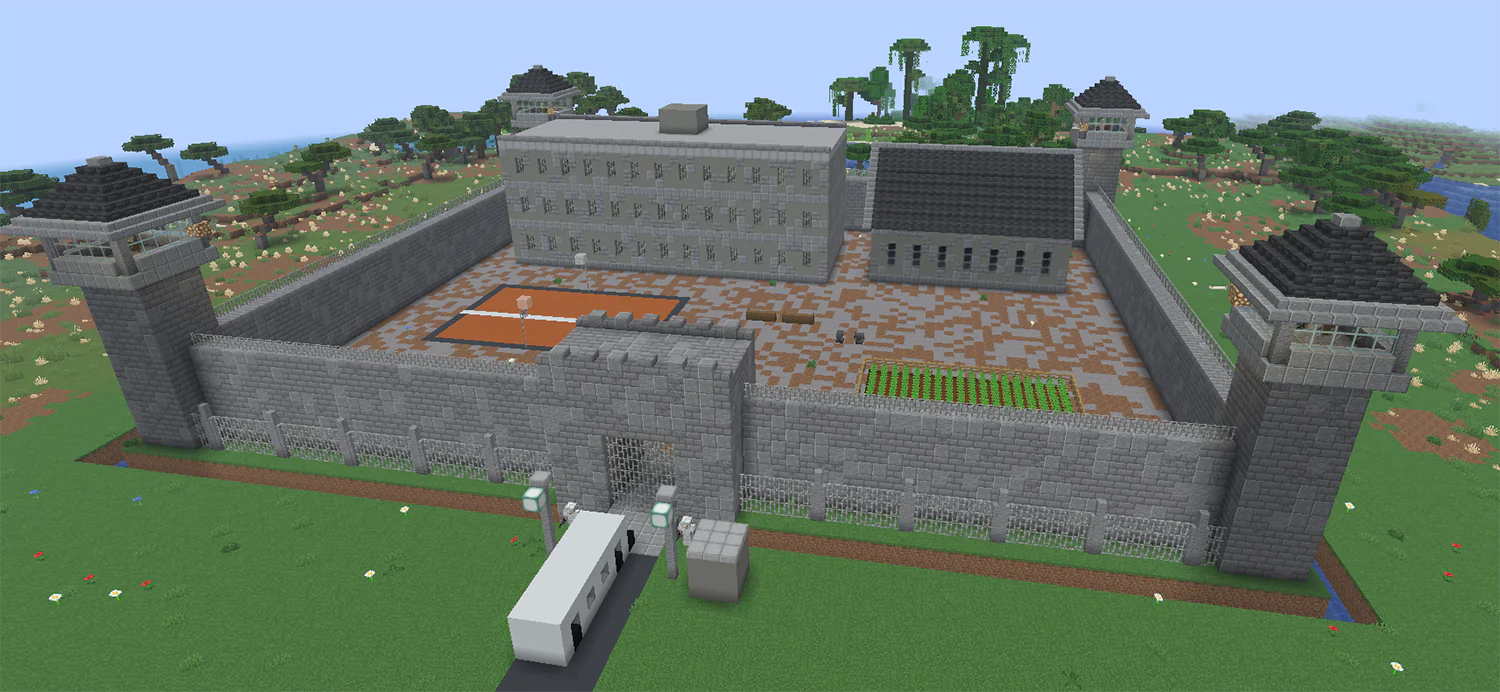 Minecraft prison with high walls, watchtowers, a cell block and exercise yard