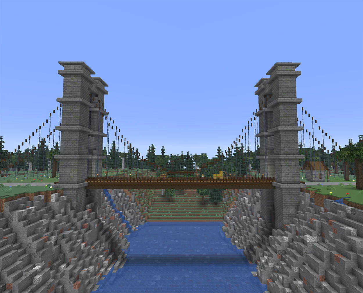 Minecraft suspension bridge with stone towers and chains over a river